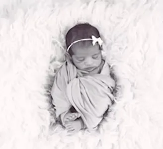 Swaddled newborn resting on fluffy white blanket