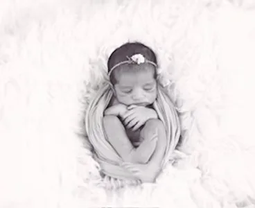 Curled-up newborn wrapped snugly in a wrap